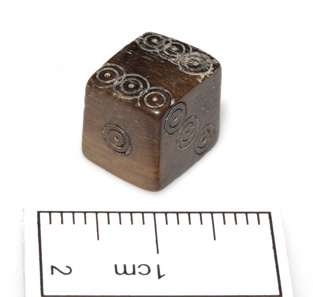 Medieval die with scale, showing the tiny size of this exquisite object